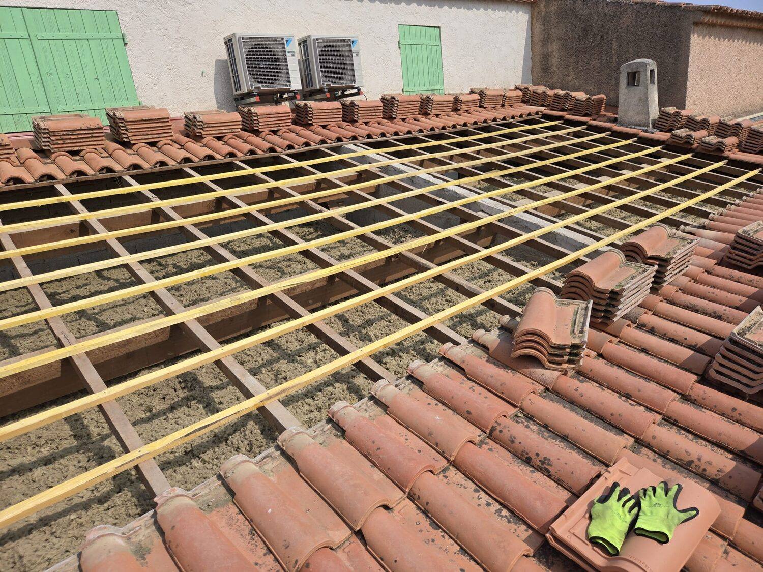 Toiture rénovée en tuiles panachées dominant un village varois