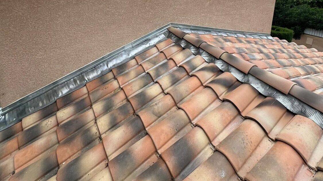 Solin en zinc le long d'un mur et faîtage en tuiles canal sur une toiture du Var, zone typique d'entrée d'eau