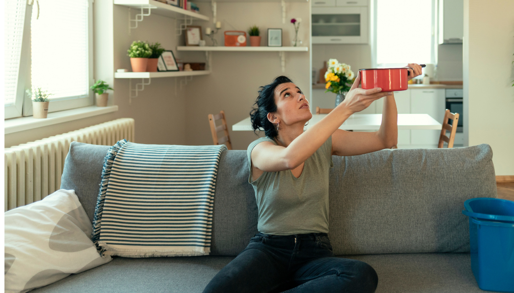 personne qui récupére la fuite du toit dans son salon